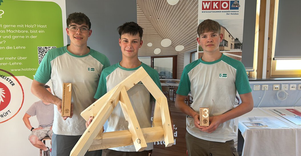 Drei Lehrlinge der Graf‑Holztechnik zeigen deren Pokale sowie das Bauwerks welches im Rahmen des Landeslehrlingswettbewerb der Zimmerer erarbeitet wurde