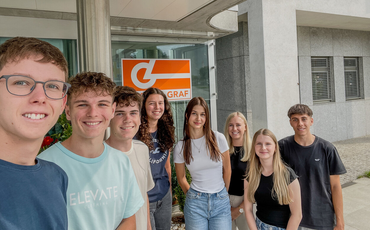 Gruppe von Praktikanten macht Selfie vor Leyrer + Graf Firmengebäude