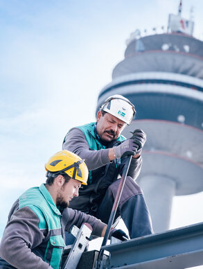 Graf‑Holztechnik Mitarbeiter arbeiten im Hintergrund ein imposanter Turm